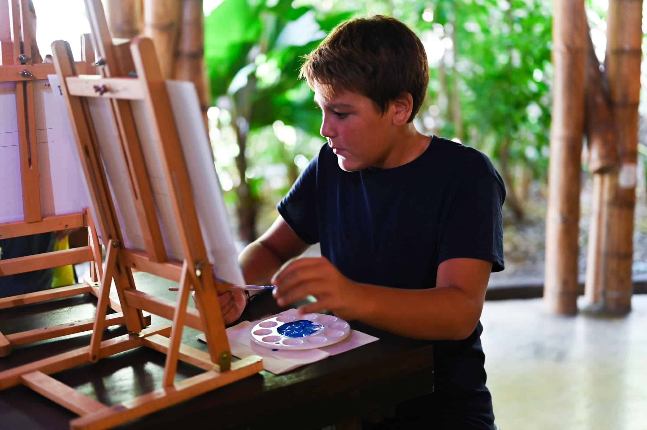 student painting with blue paint on a canvas