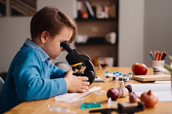 young boy looking through telescope at school