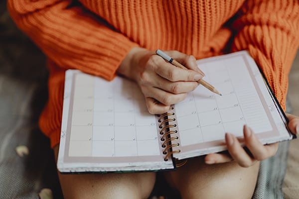 woman writing on her daily planner